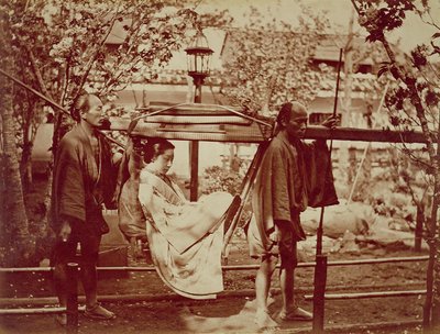 A Geisha being carried in a litter by Japanese Photographer